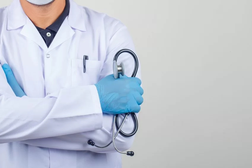 doctor crossing arms while holding stethoscope in white coat scaled